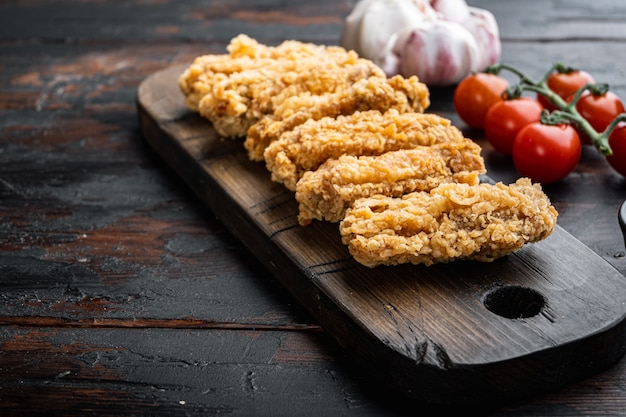 Piezas de alas de pollo frito en la vieja mesa de madera oscura.