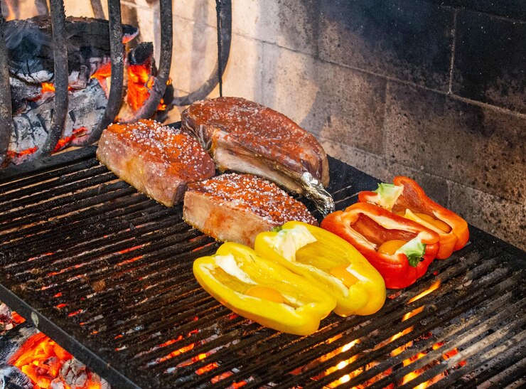 Foto piezas de carne y pimienta asadas en una parrilla típica uruguaya llamada parrilla