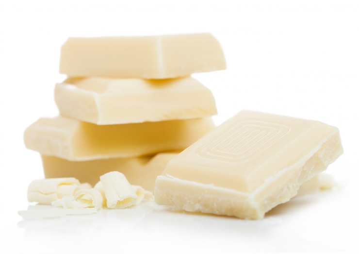 Foto piezas de chocolate blanco y rizos aislados en blanco.