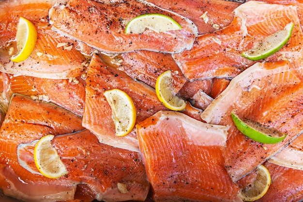 Piezas de filete de pescado rojo con pedazos de limón y lima en la parte superior