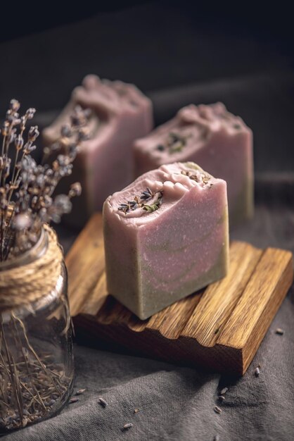 Foto piezas de jabón natural de lavanda hecho a mano en un plato de jabón de madera y en un fondo de tela oscura con flores secas concepto de cosméticos orgánicos un pasatiempo útil e interesante una hermosa tarjeta postal