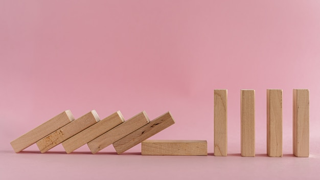 piezas de madera cayendo sobre fondo rosa