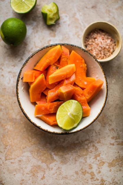 Piezas de papaya con lima y sal en el plato para cocinar comida