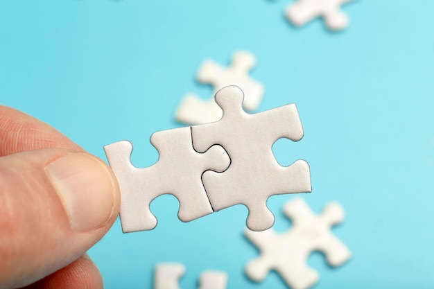 Las piezas del rompecabezas están conectadas piezas blancas del rompecabezas en la mano sobre un fondo azul socio comercial