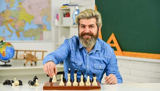 Piezas y tableros maestro de escuela feliz pensando en atacar y capturar piezas de ajedrez del oponente