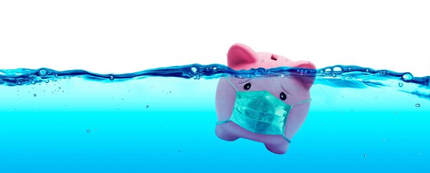 Foto piggy bank usando uma máscara de proteção afogando-se sob a água conceito de proteção e poupança para o risco