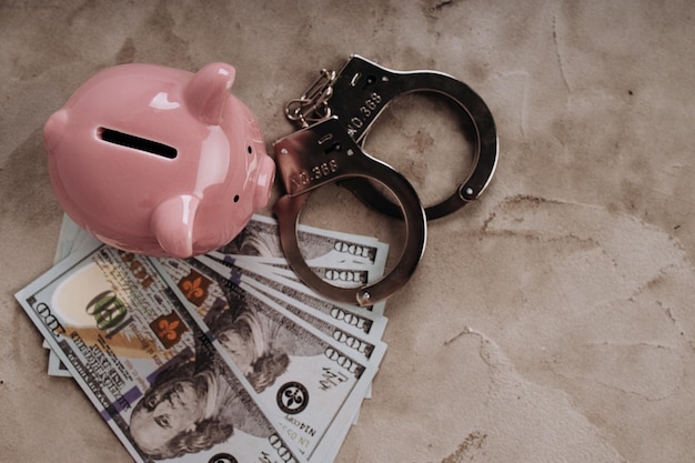 Piggy y dinero con esposas Concepto de crimen y fraude Quiebra o pérdida de ahorros