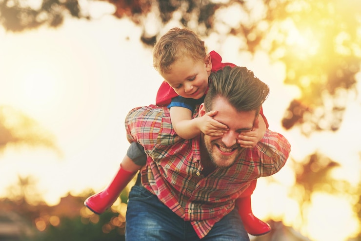 Foto piggyback pai e filho com as mãos sobre os olhos no jardim para jogos família e felicidade na natureza para férias homem filho e apoio no quintal para aprender crescimento e desenvolvimento com cuidado