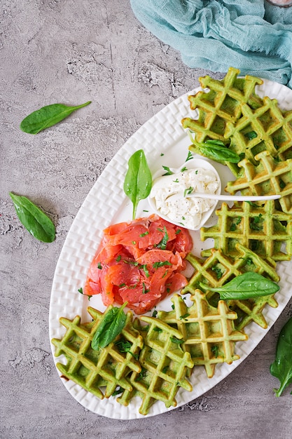 Pikante Waffeln mit Spinat- und Frischkäse, Lachs in der weißen Platte. Leckeres Essen. Ansicht von oben. Flach liegen