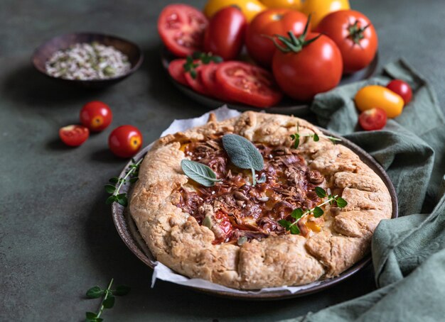 Pikanter Tomatenkuchen mit offener Torte oder Galette mit Tomaten und Käse mit aromatischen Kräutern