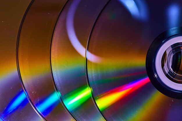 Pila abstracta de cuatro CD con conos de luz reflectantes del arco iris