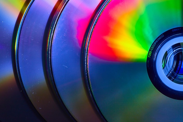 Pila abstracta de cuatro CD con explosión de luz reflectante en la superficie