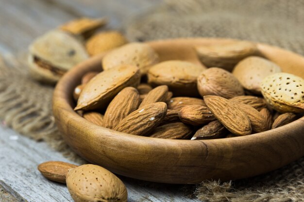 Pila de almendras crudas peladas y almendras crudas con conchas en la mesa de madera. De cerca