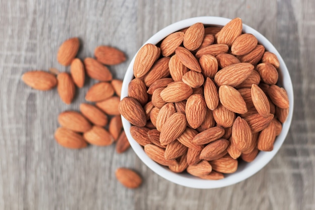 Pila de almendras tuerca en un recipiente de tiempo contra el fondo de madera