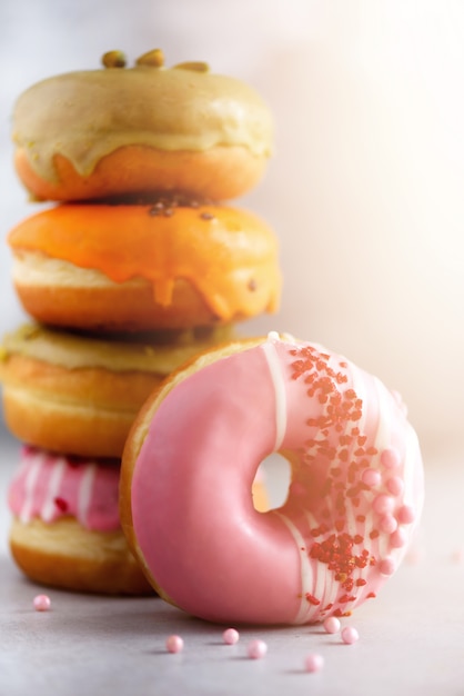 La pila de anillos de espuma clasificados coloridos esmaltados con asperja en fondo gris del cemento. Rosquillas dulces para niños.