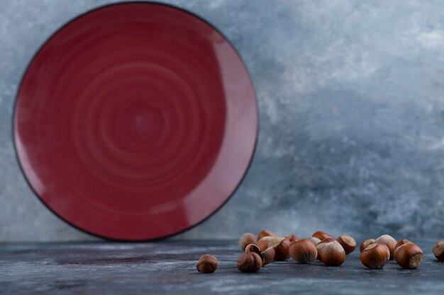 Foto pila de avellanas sin cáscara orgánicas con placa roja vacía.