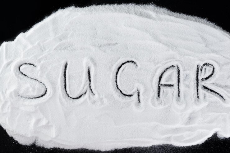 Foto pila de azúcar blanco con la inscripción azúcar en un fondo negro azúcar de uva vista superior