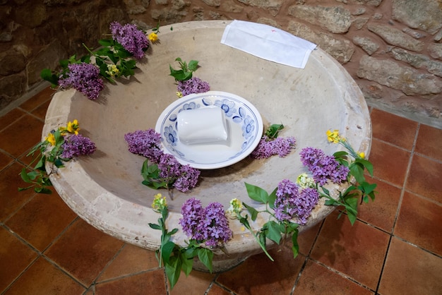 Pila bautismal con agua bendita decorada con flores preparada para un bautizo