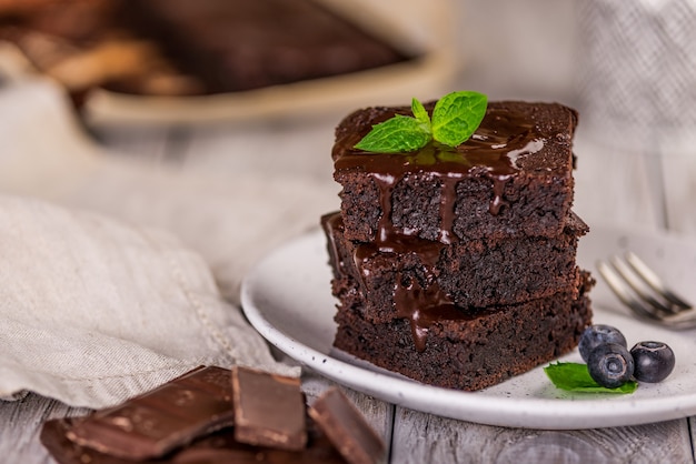 Una pila de brownies de chocolate sobre fondo de madera con hojas de menta en la parte superior, panadería casera y postre.