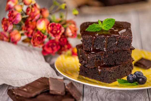 Una pila de brownies de chocolate sobre una superficie de madera con hojas de menta en la parte superior, panadería casera y postre