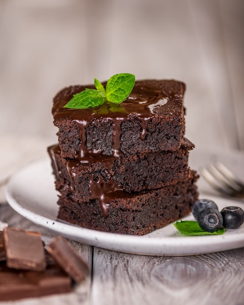 Una pila de brownies de chocolate sobre una superficie de madera con hojas de menta en la parte superior, panadería casera y postre