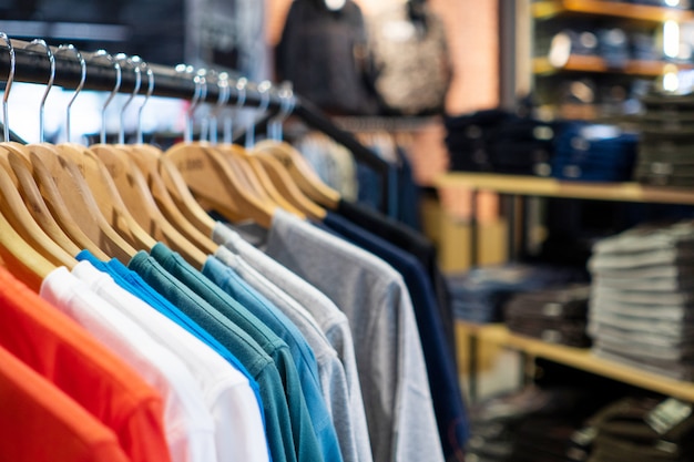 Pila de camiseta colorida colgando en grandes almacenes de moda en el centro comercial