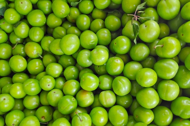 Pila de ciruelas verdes agrias en un puesto en el mercado