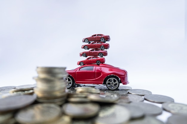 Una pila de coches de juguete con monedas contra un fondo blanco