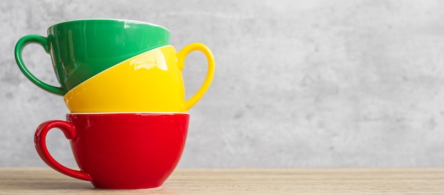 Pila de coloridas tazas de café en el fondo de la pared en el café Taza de cerámica de color verde amarillo y rojo en la mesa en casa Concepto del día internacional del café