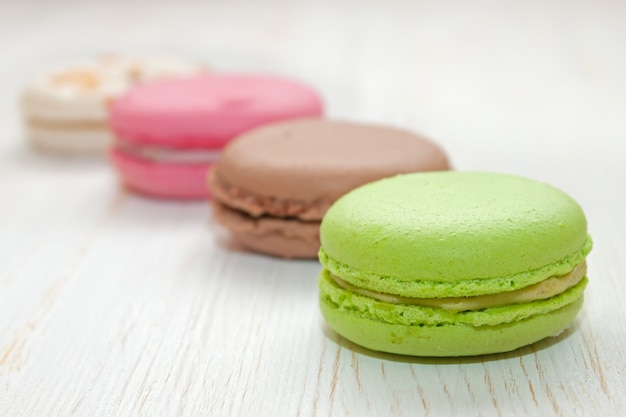 Una pila de coloridos macarrones de postre francés tradicional en la mesa de madera blanca.