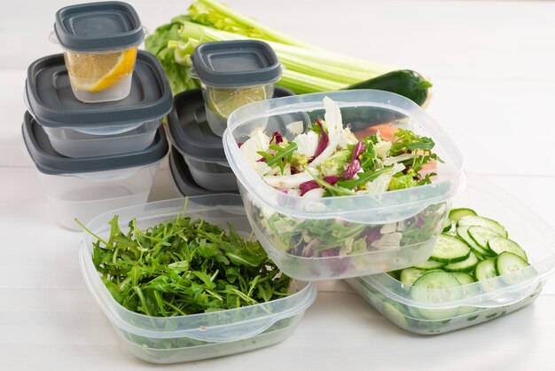 Una pila de contenedores de plástico y verduras crudas en la mesa