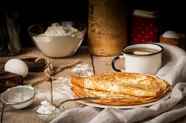 Pila de crepes e ingredientes para cocinar en una mesa