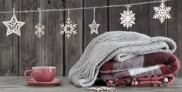 Pila de cuadros, taza de té y adornos navideños sobre fondo de madera