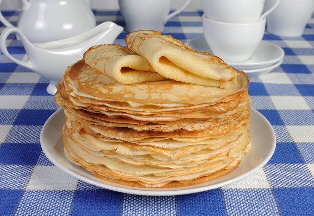 Pila de deliciosos panqueques en la mesa con crema agria