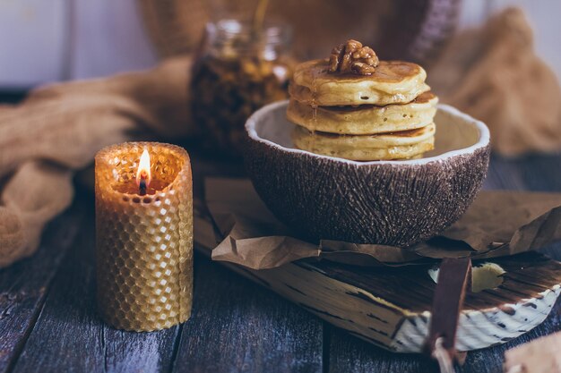 Pila de deliciosos panqueques con miel, nueces sobre fondo de madera