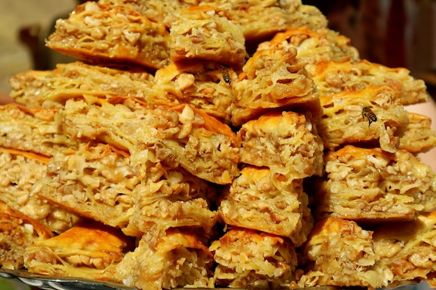 Pila de deliciosos pasteles Baklava que atraen a las abejas hambrientas en el mercado local de Armenia