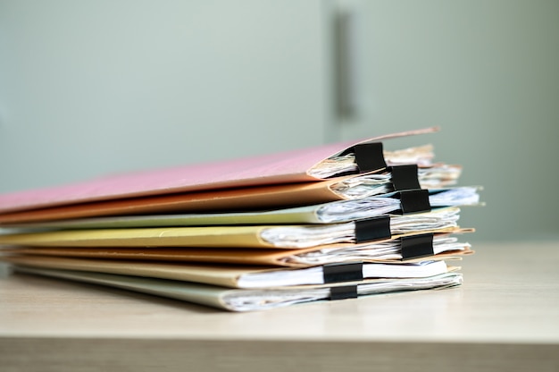 Pila de documentos con carpeta de clip colocada en un escritorio en una oficina comercial.