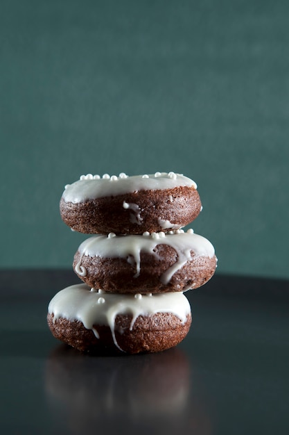 Una pila de donas de chocolate caseras con glaseado blanco y bolas decorativas