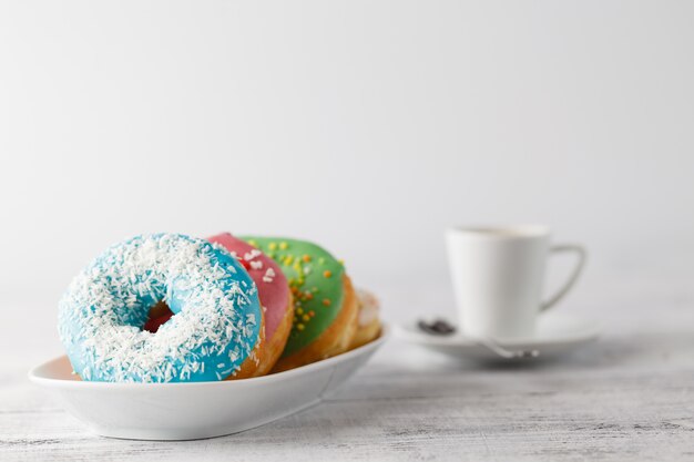 Pila de donas heladas con taza de café en la mesa