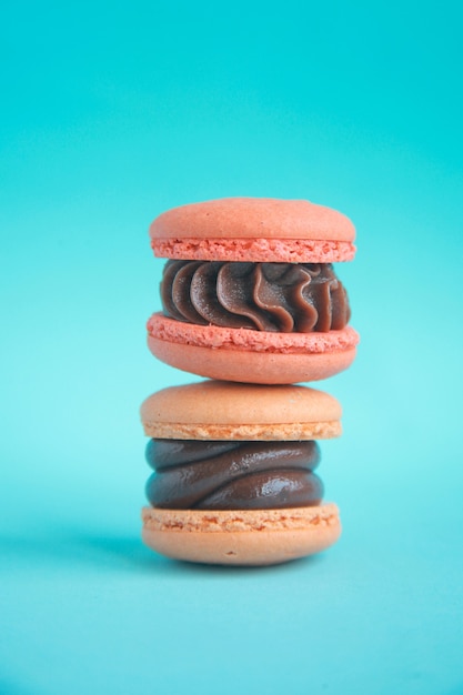 Pila de dos macarrones coreanos con crema de chocolate en la pared azul brillante