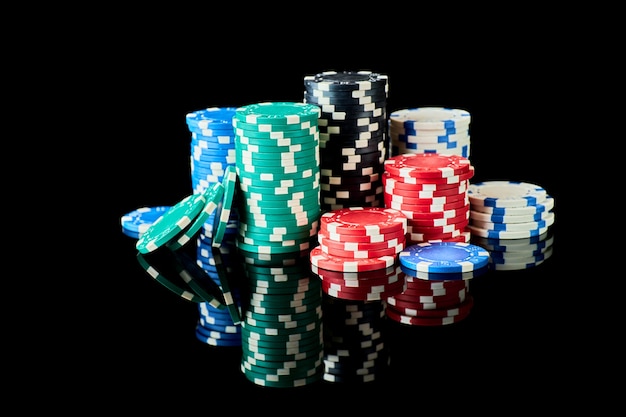 Pila de fichas de juego de casino aislado sobre fondo negro reflectante