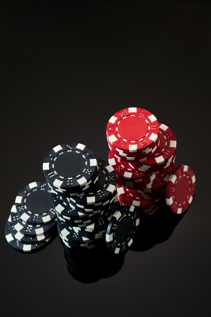 Pila de fichas de juego de casino aislado sobre fondo negro reflectante