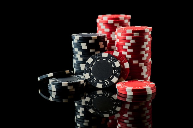 Pila de fichas de juego de casino aislado sobre fondo negro reflectante