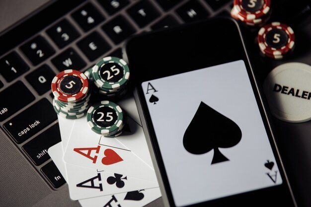 Pila de fichas de juego, smartphone y naipes en un keaboard portátil. De cerca. Concepto de casino online