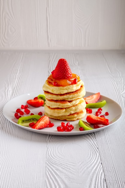 Pila de flapjacks calientes servido con fresas frescas y kiwi