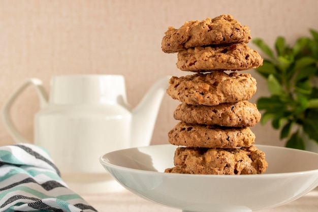 Una pila de galletas de almendras en un plato con una tetera al fondo