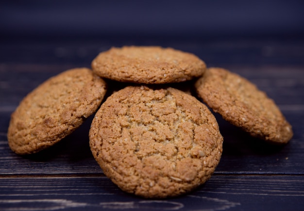 Una pila de galletas de avena de grano entero sobre un fondo de madera oscura.