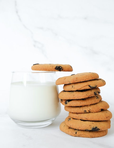 Pila de galletas de chispas de chocolate caseras y vaso de leche en mármol