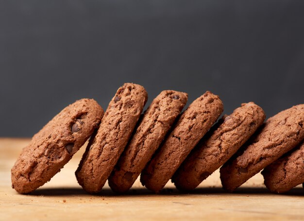 Pila de galletas de chispas de chocolate redondas al horno sobre una mesa de madera marrón