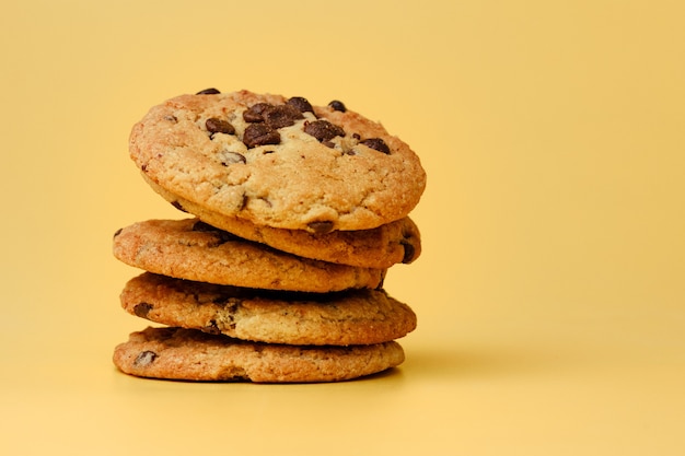 Pila de galletas con chispas de chocolate sobre fondo amarillo